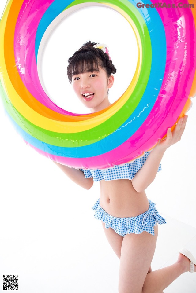 A young girl in a bathing suit holding an inflatable ring.