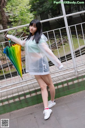 A woman standing on a train platform holding an umbrella.