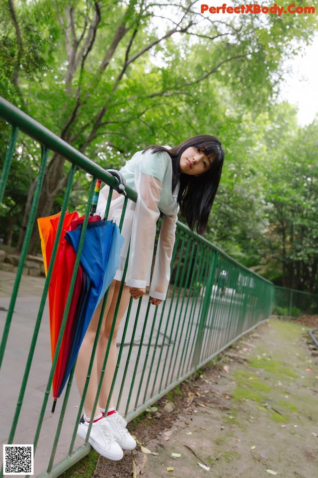 A woman standing on a bridge holding an umbrella.