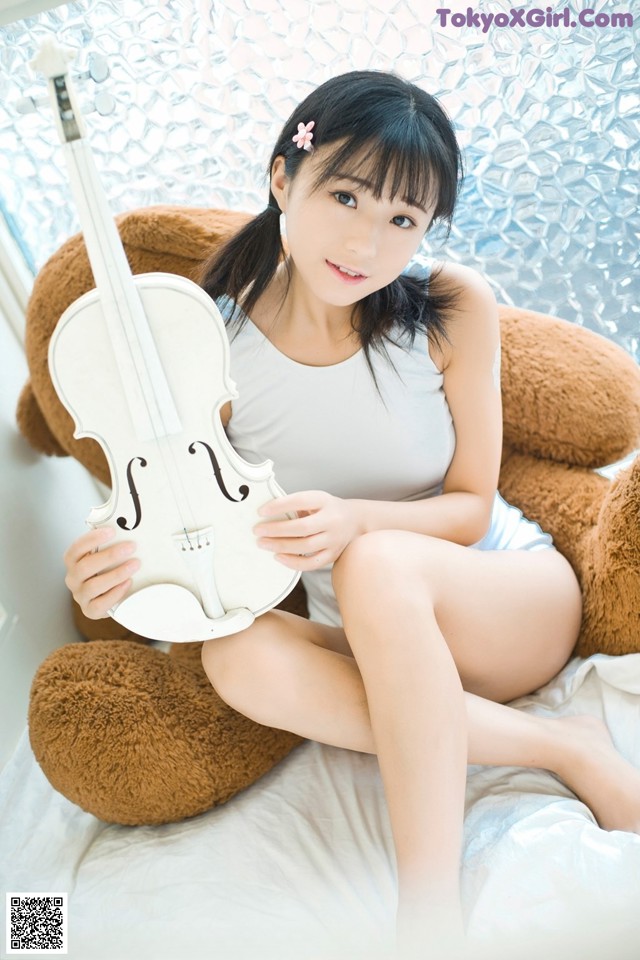 A woman sitting on a bed holding a violin.