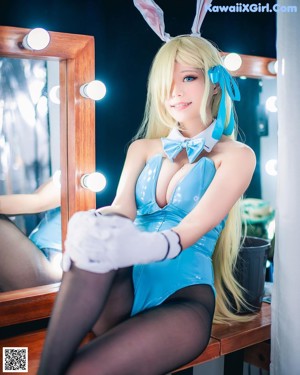 A woman in a blue bodysuit and bunny ears posing for a picture.