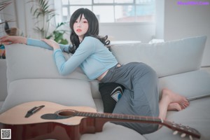 A woman laying on a couch with her back to the camera.