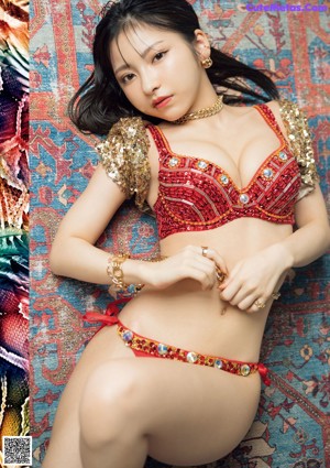 A woman in a red and gold outfit laying on a rug.