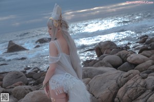 A woman in a white dress standing on a wooden deck.