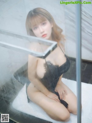 A woman in a black bikini standing in front of a window.