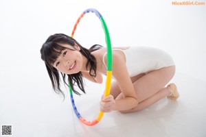 A woman in a white leotard sitting on the floor.