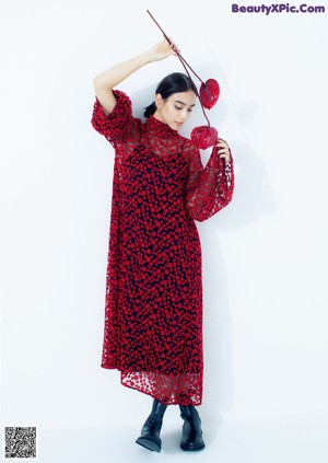 A woman in a red dress holding a red flower.