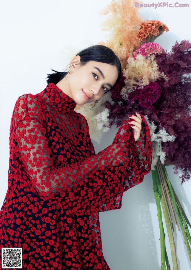 A woman in a red dress holding a bunch of flowers.