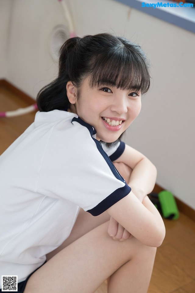 A young woman sitting on the floor with her legs crossed.