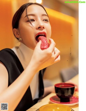 A woman eating sushi with red caviar on a plate.