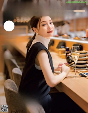 A woman sitting at a table eating a piece of food.