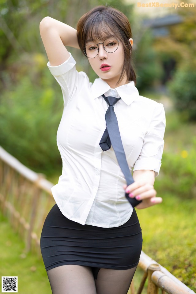 A woman in a white shirt and black skirt posing for a picture.