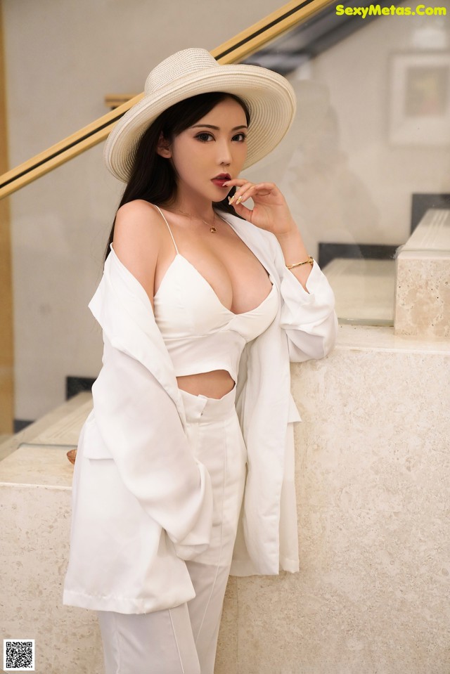 A woman in a white suit and hat posing for a picture.