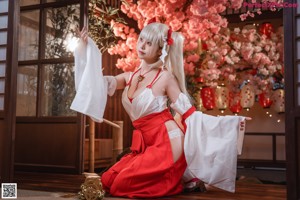 A woman in a white dress sitting on a wooden floor.