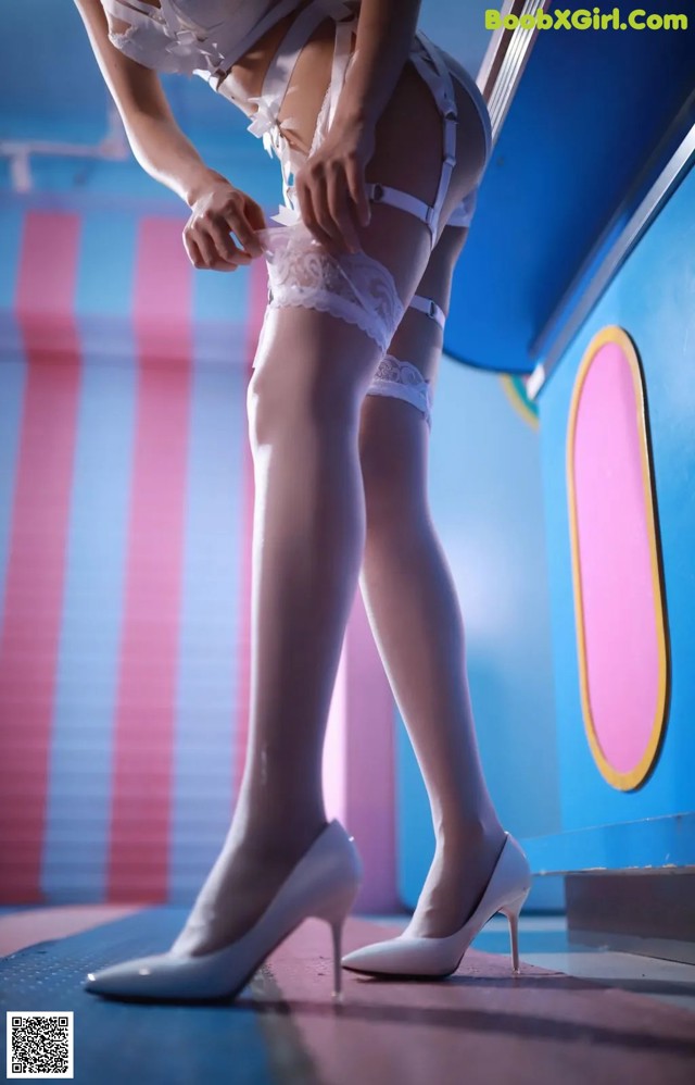 A woman wearing white stockings and high heels in a room.