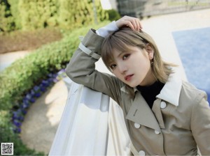 A woman wearing a trench coat standing in front of stairs.