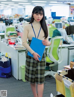 A woman sitting on a green chair in an office.