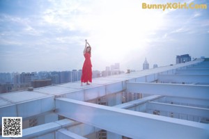 A woman in a red dress standing on a ledge.