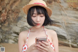 A woman in a red and white bikini sitting on a rock.