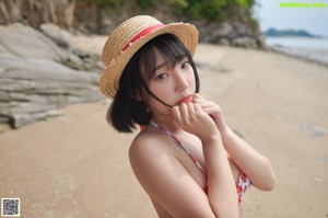A woman in a bikini sitting on the sand.