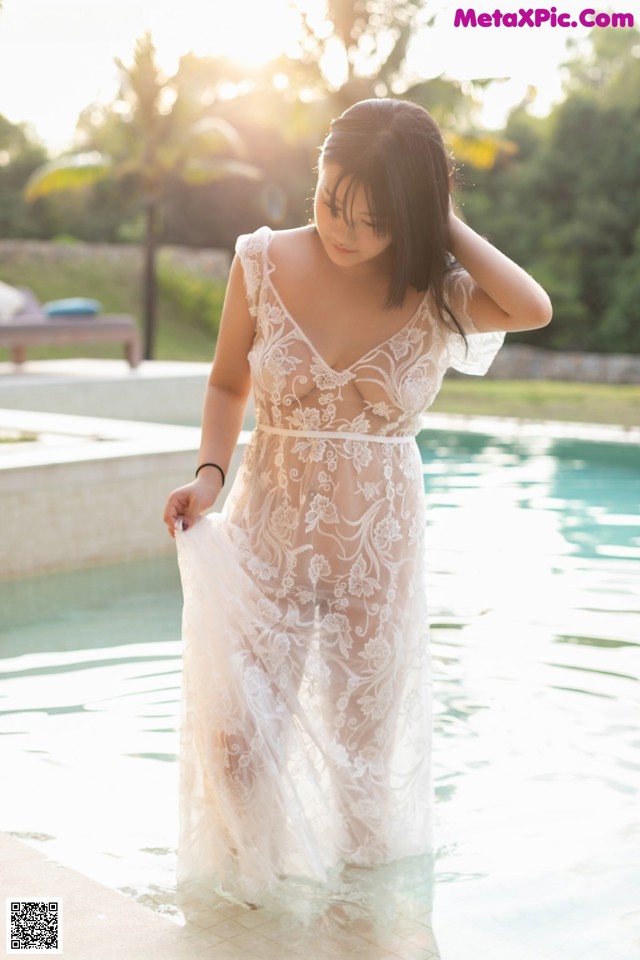 A woman in a white dress standing in a pool.