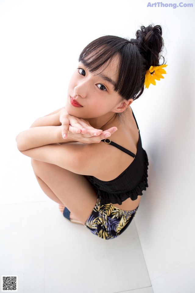 A woman with a flower in her hair sitting on the floor.