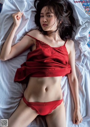 A woman in a red dress laying on a bed.