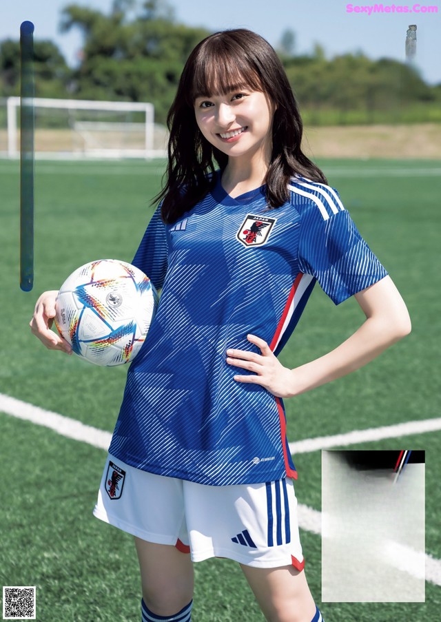 A woman holding a soccer ball on a soccer field.