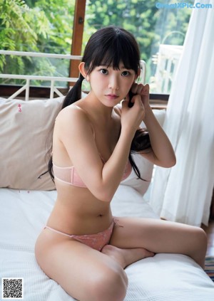 A woman in a white bra and panties sitting on a blue chair.