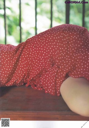 A woman in a red dress looking up at the sky.