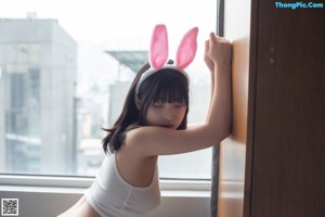 A woman wearing bunny ears sitting on a bed.
