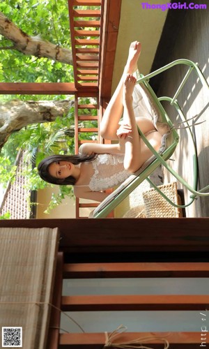 A woman in a white dress sitting on a green chair.