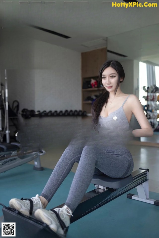 A woman sitting on a rowing machine in a gym.