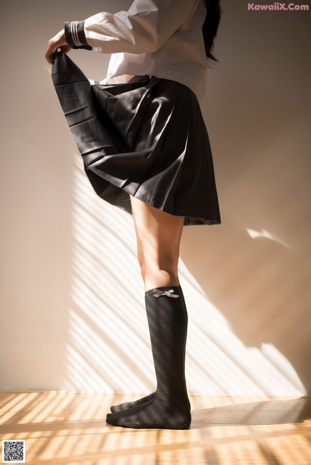 A woman in a white shirt and black skirt holding a black skirt.