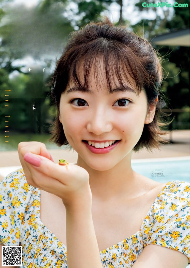 A young woman holding a small frog in her hand.