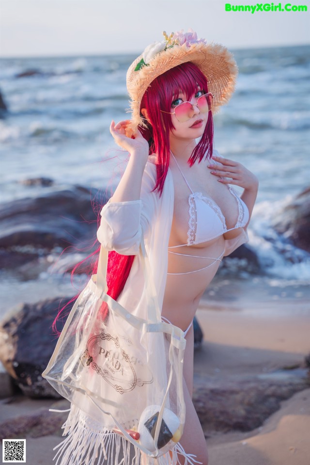 A woman in a white bikini and straw hat on the beach.