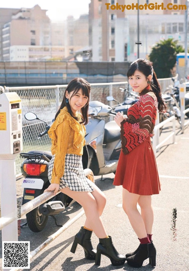 A couple of women standing next to each other near a parking meter.