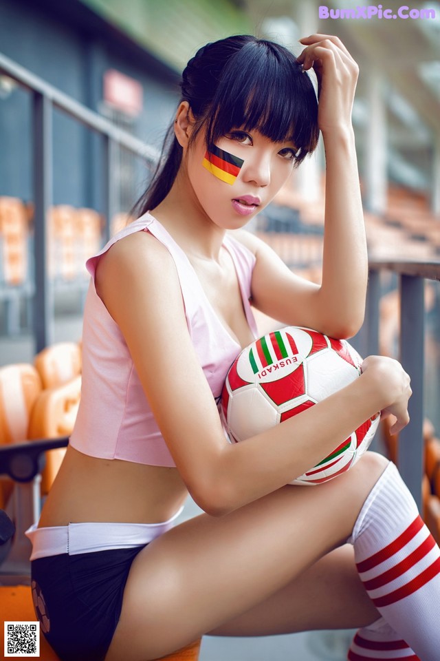 A woman sitting on a bench holding a soccer ball.