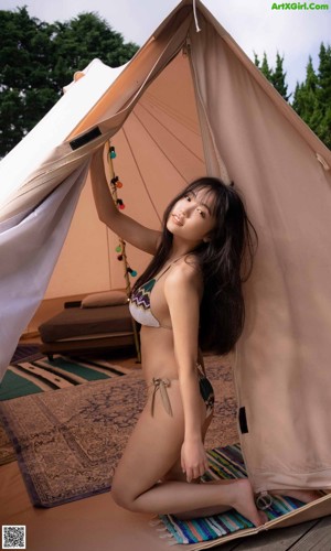 A woman in a white bodysuit standing on a beach.