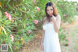 A woman in a blue and white bikini posing next to a tree.