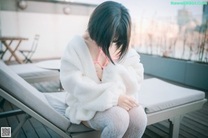 A woman in a pink bikini sitting on a white couch.