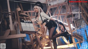 A woman in a black and white outfit holding a whip.