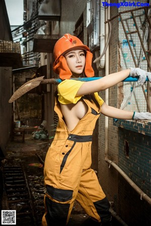 A woman wearing a hard hat and a yellow shirt.