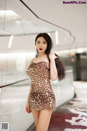 A woman in a leopard print dress holding a cell phone.