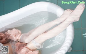 A woman sitting in a bathtub with her legs crossed.