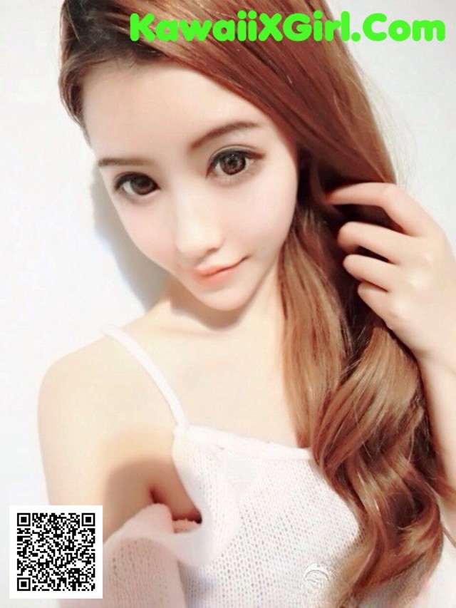 A woman with long brown hair wearing a white top.