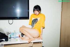A woman sitting on the floor holding a bottle of beer.