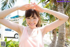 A naked asian woman standing in front of a pink building.