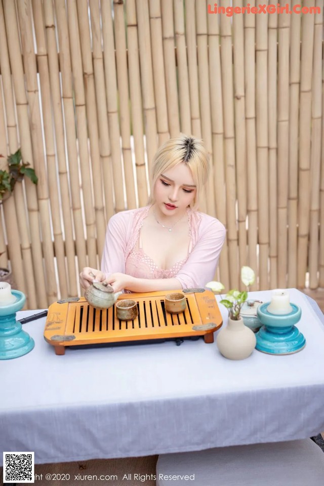 A woman sitting at a table with a tray of tea.