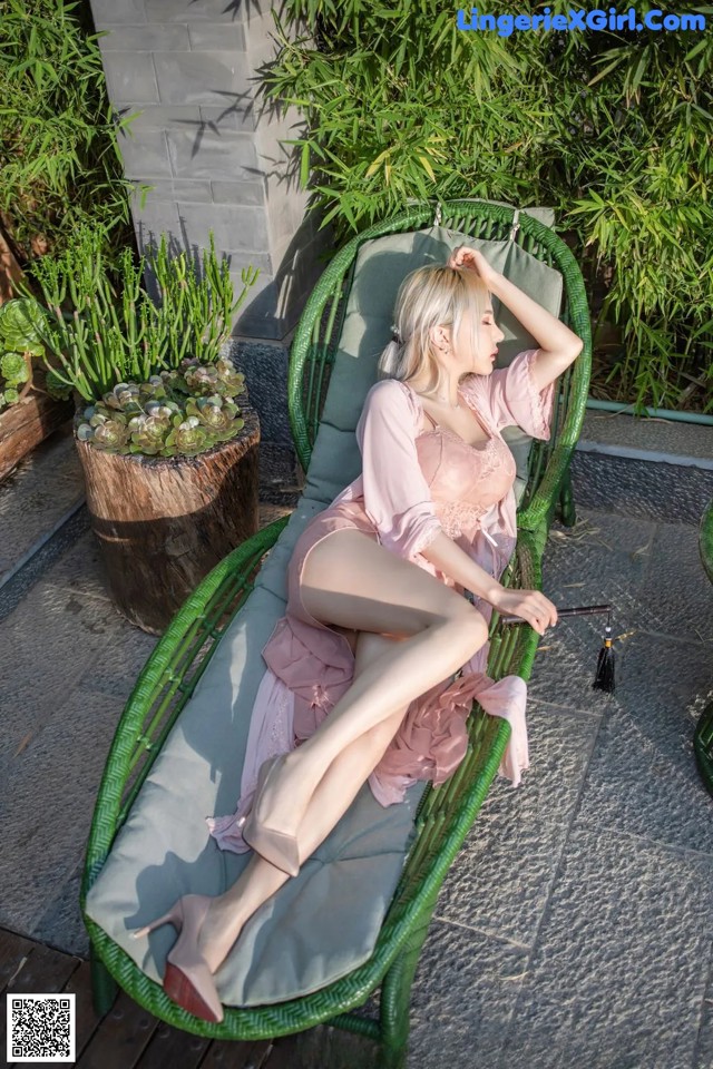A woman in a pink dress sitting on a green chair.